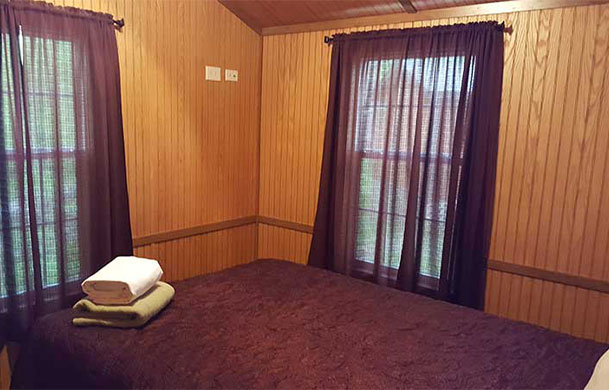 Deluxe cabin bedroom with queen bed at Adventure Bound Southwoods